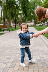 autistic child in denim clothes holding hands of mother in park