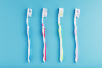 Toothbrushes of different colors in a row on a blue background.