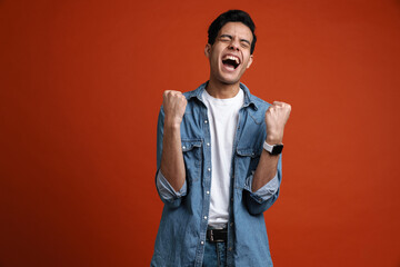 Excited hispanic man in shirt screaming while making winner gesture