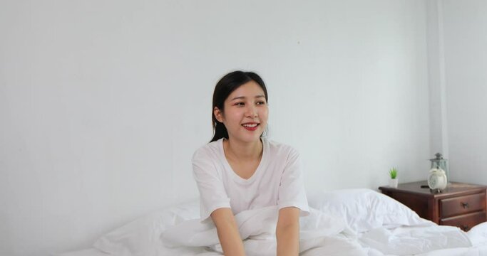 A young Asian woman sat with a refreshing smile, welcoming a bright new morning.