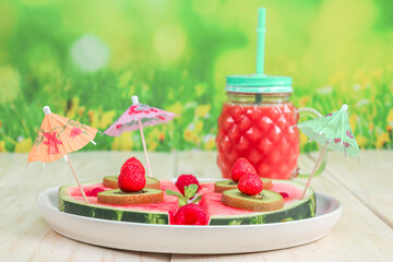 Watermelon with fruits and berries in a plate and juice in a glass.