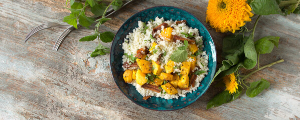 a plate of couscous with pumpkin on a wooden table