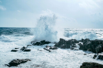Fototapeta na wymiar Waves rush onto the rocks. Stormy weather. Powerful blow of the sea wave.