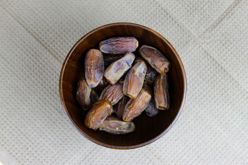 Wooden bowl with dates on the table. Fruit on a wooden tray. Fruit dates. Walnut kernels. The concept of Ramadan.