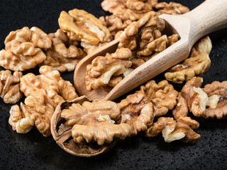 wooden scoop in heap of peeled walnuts closeup
