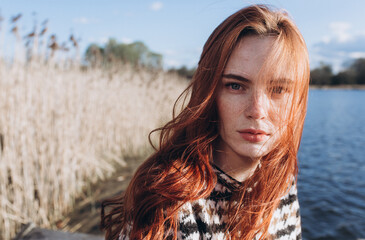 Red hair girl with freckled face outdoors near the lake. Natural beauty, eco lifestyle, nature...