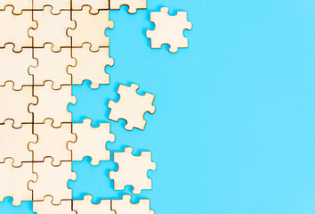 Fototapeta na wymiar Wooden jigsaw puzzle on a blue paper background