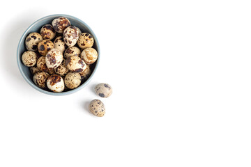 Top view. A blue bowl with quail eggs on a white background. Free space for text.