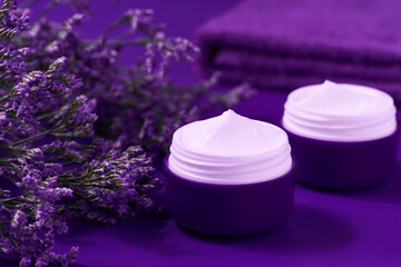 Obraz na płótnie Canvas Night hygienic cream skincare product in purple plastic jar with towel on table.