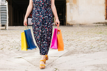 Impersonal photo of a shopping woman with colored bags in her hands.