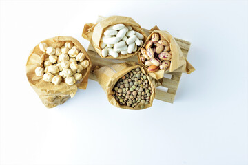 Zenithal view, healthy food bags, assortment of dried legumes on pallet. Copy space. Minimalist and idea. White background.	