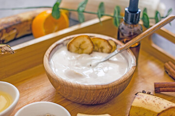 Homemade cosmetic cream with banana from natural ingredients. Banana face mask at home for wellness skin and body care. Diy natural cosmetics concept background