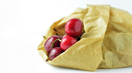 Close up. Cherries in kraft paper bag, on white background.