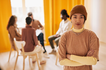 Waist up portrait of Asian teenage girl looking at camera during therapy session in support group,...