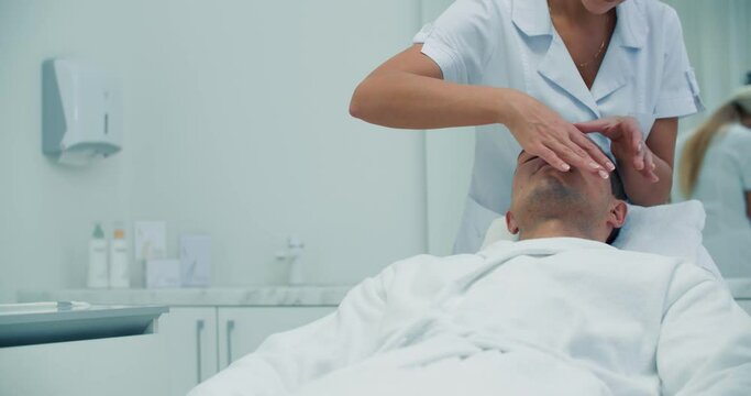 Close-up face of a male client is having a non-injection mesotherapy procedure on his forehead by using Dermadrop TDA device.