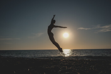 dancer jumps on the beach at sunset over the sea, ballerina salta sulla spiaggia al tramonto sul mare