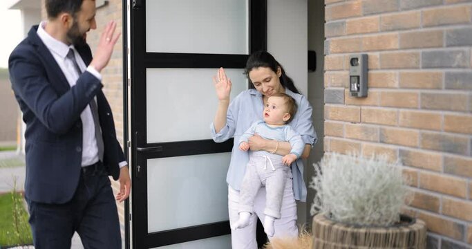 Businessman going out at work, kissing and saying goodbye to his wife and baby at the door way of the house