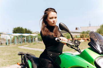 Fototapeta na wymiar Beautiful girl with dark hair sits on a green motorcycle.