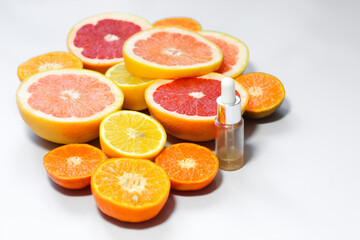 Face serum with vitamin c with different citrus fruits on a white background.