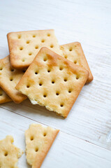 Crispy cracker on a wooden white background. Square dry crackers on a wooden table have free space for text, top view.