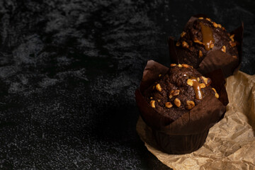 Chocolate delicious tall muffins wrapped in dark packaging. Dark mood food photography.