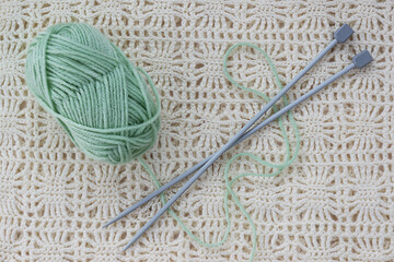 Threads and knitting needles on the background of knitted fabric. Horizontal orientation, top view. 