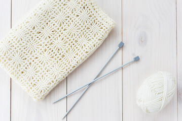 Knitting needles with threads for knitting on a wooden table. Horizontal orientation, top view.