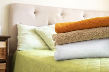  Stack of clean colorful towels on bed. Bedroom background.