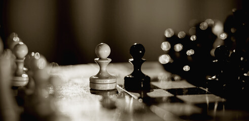 Two pawns - black and white. Wooden chess pieces on the chessboard.