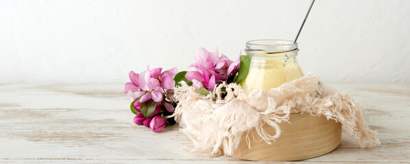 glass jar with mango panna cotta and apple blossoms on a light table