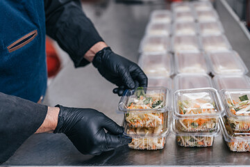 Food in disposable dishes ready for delivery. The chef prepares food in the restaurant and packs it in disposable lunch boxes. - 435490223
