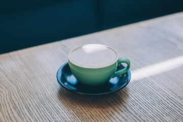 Cup of coffee on a rustic wooden table in a cafe.