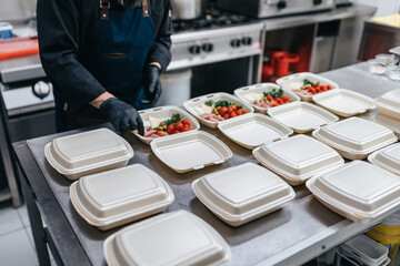 Food in disposable dishes ready for delivery. The chef prepares food in the restaurant and packs it...