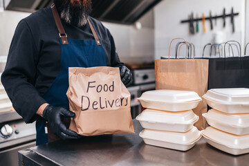 Food in disposable dishes and bag of kraft paper ready for delivery.