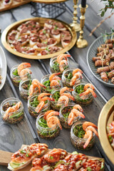 Delicious fresh seafood, shrimp with fresh vegetables. buffet table with lots of delicious snacks. canapes, bruschetta, and little desserts on wooden plate board