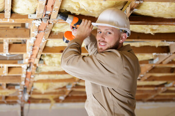 tradesman using drill on wooden framework of ceiling