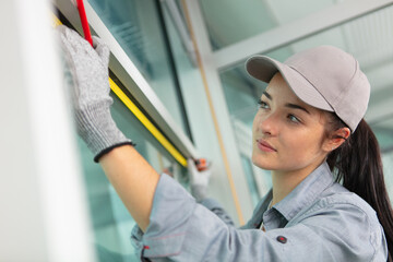 young female worker measuring window