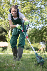 woman gardener in uniform mows the grass trimmer