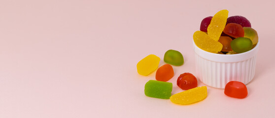 marmalade and sweets on beige background with copy space. Multi colored candies in a bowl