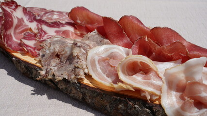 Delicious cutting board of fresh cold cuts on wooden plate. Bacon, coppa, salami and bresaola....