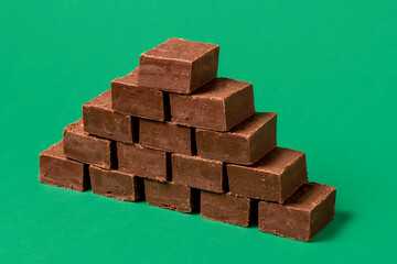 Chocolate fudge pile isolated on a green background.