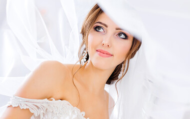 close-up of beautiful bride with makeup and hairstyle covered with veil. Wedding concept.