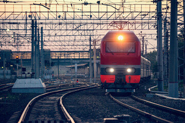 Passenger train departs from the station at sunset.
