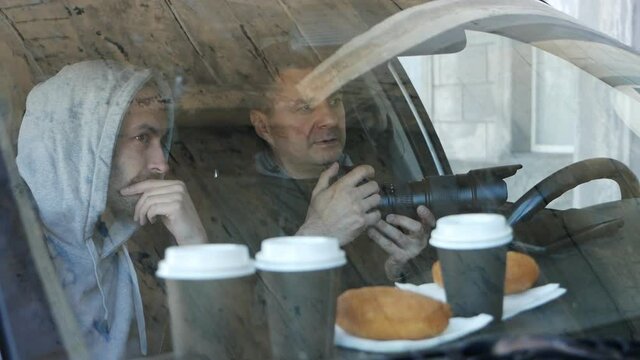 Private detectives or spies are monitoring the object of observation. The man secretly takes pictures from the car window