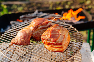 Grilled bacon on the background of the grill. Smoked bacon, fire burns in the back