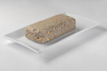 Homemade halva with peanuts on a white plate. White background. Focus on the front of the halva