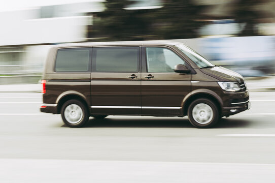 Fast moving Volkswagen Transporter T6 on the city road. Brown minivan rides on street. Commercial auto in fast motion with blurred background. speeding in the city concept