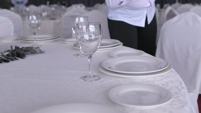 Waiter serves banquet table with blue gloves. Spoons, forks, glasses and knives. Coronavirus quarantine COVID-19 virus flu epidemic. Service staff in restaurant. close up. Banquet service
