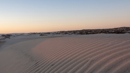 Fototapeta na wymiar Soft rays of sunlight visible on pattern of sand dune ripples