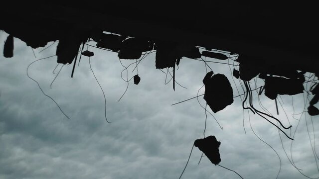 Silhouettes of concrete and metal structures of a destroyed house against the sky. Consequences of war or earthquake